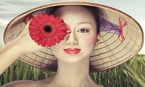 © photoflow - Fotolia | Beautiful vietnamese girl in a traditional hat is holding flower