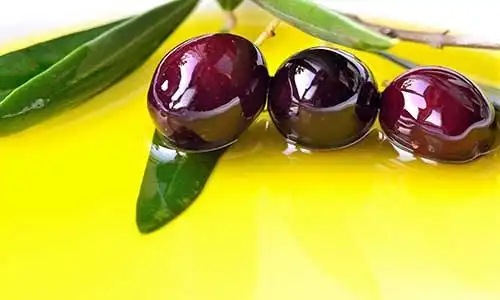 © travelbook - Fotolia | Olive oil background with black olives closeup