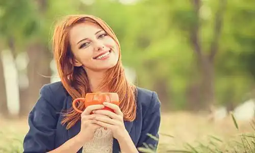 © Masson - Fotolia | Redhead girl with orange cup at outdoor