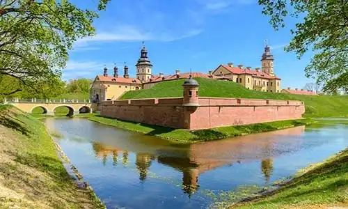 © stitchik - Fotolia | View on medieval castle Nesvizh, moat with water and fortress wa